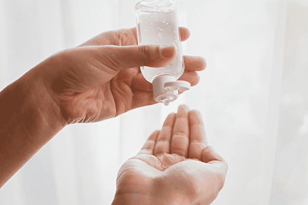 Hands holding a clear liquid bottle with a pump dispenser.