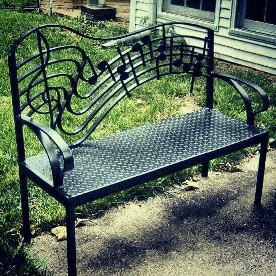 Black metal bench with decorative backrest.