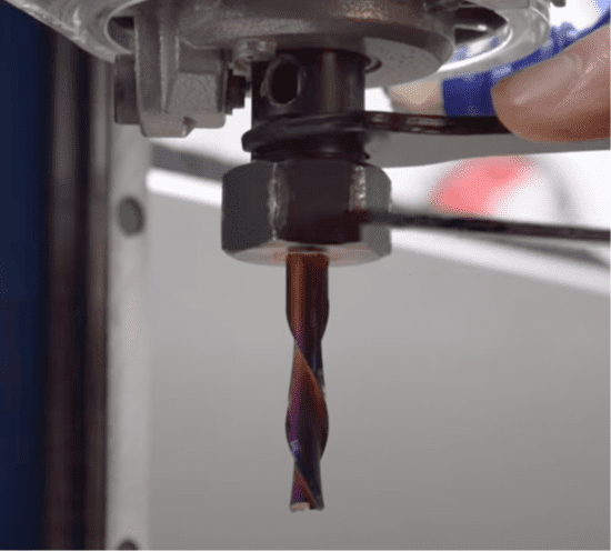 A close-up of a drill bit held by fingers.