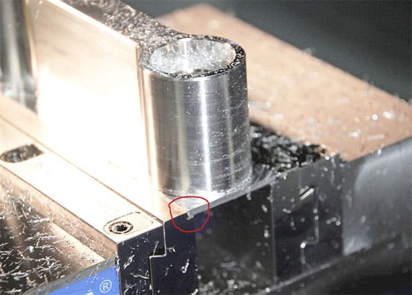 Metal part on machine shop workbench with dovetail knife edge jaw.