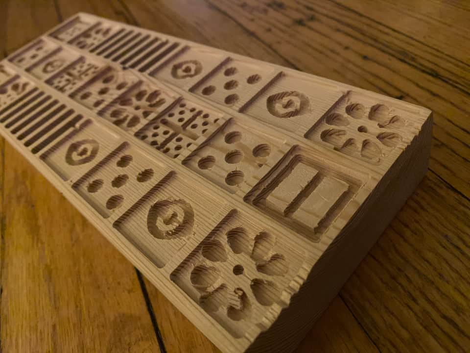 Wooden mold with intricate designs and patterns made of light-colored wood.
