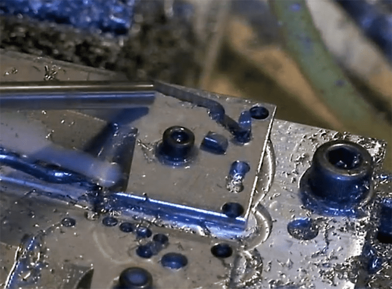 Metal workpiece with holes and features machined into it.