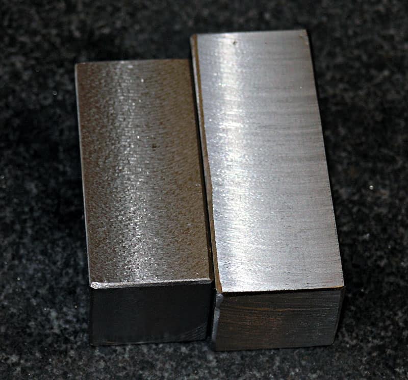 Two metal blocks with brushed finish on a dark background.