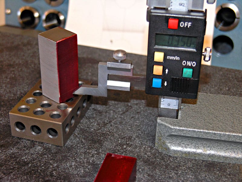 Digital caliper on dark grey countertop with metal object.