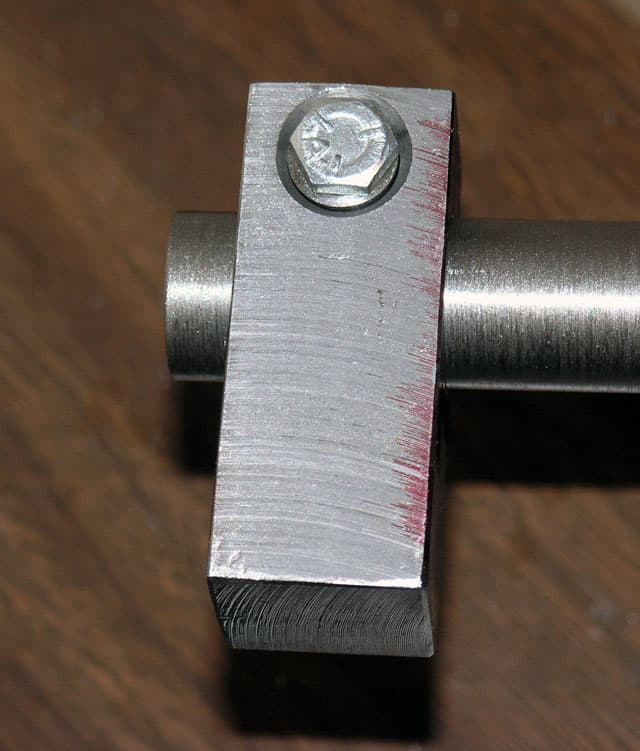 Metal tool or component with bolt and cylindrical shaft on wooden surface.