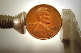 A penny being compressed by two metal objects.