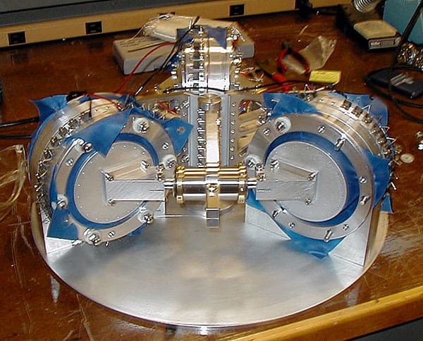 Silver metal device with blue tape on wooden table.