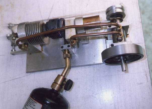 Industrial device with copper tubing and black component on metal plate over cylindrical object.