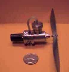 Small airplane model with propeller and wing next to a coin.