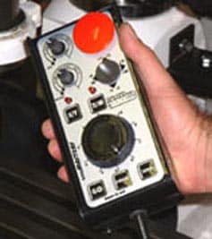A hand grasping a white and black control panel with buttons and dials.