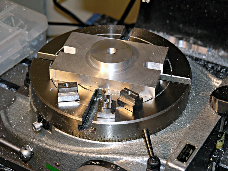 Metal fixture with four square nuts and a circular base.