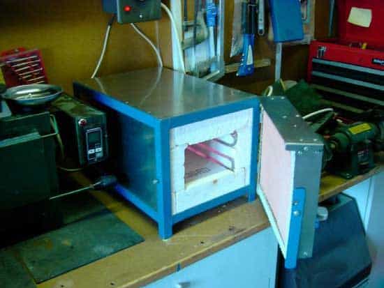 A heat treat furnace with blue metal body and white interior in a machine shop.