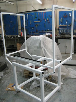 White metal frame on grey concrete floor, surrounded by tools and equipment.