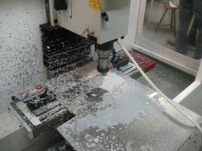 Machine tool in operation, milling or turning center with coolant system and various tools.