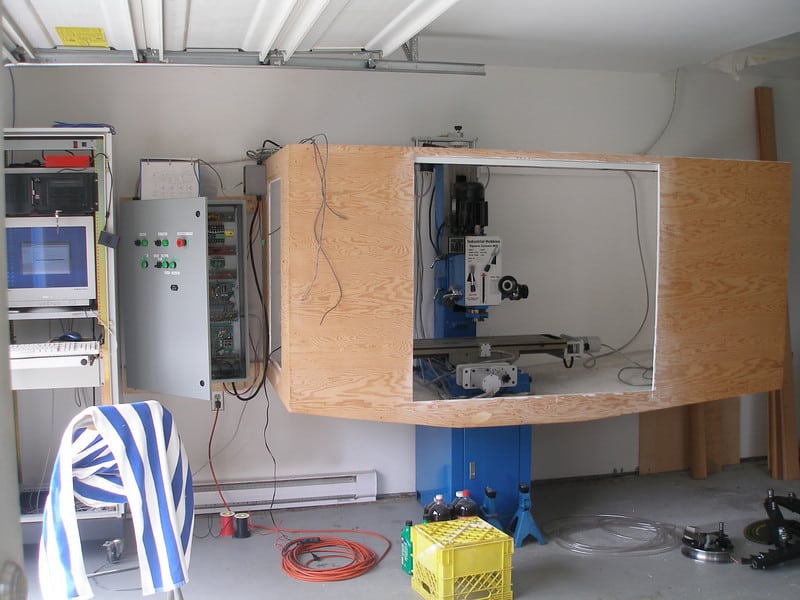 Cluttered workshop with various tools, machinery, and computers.