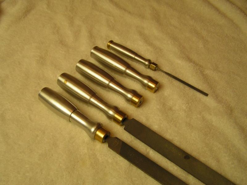 Five brass files with wooden handles arranged in staggered formation on a tan surface.