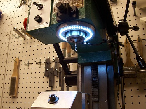 A drill press with LED ring light installed on its head in a workshop setting.