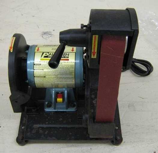 Palmgren bench grinder with sanding belt, cylindrical body, and four legs.