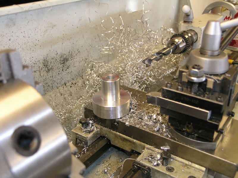 Metalworking lathe in action, with metal shavings and tools.