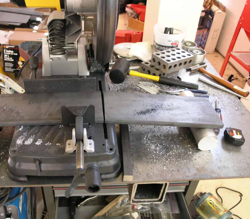 Cluttered metalworking table with saw, drill press, and vise.