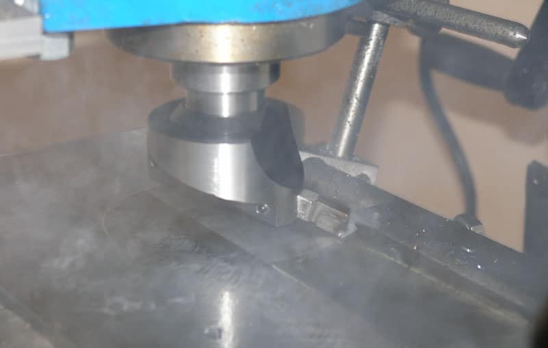 Blue metalworking tool with silver cylindrical part on metal shavings.