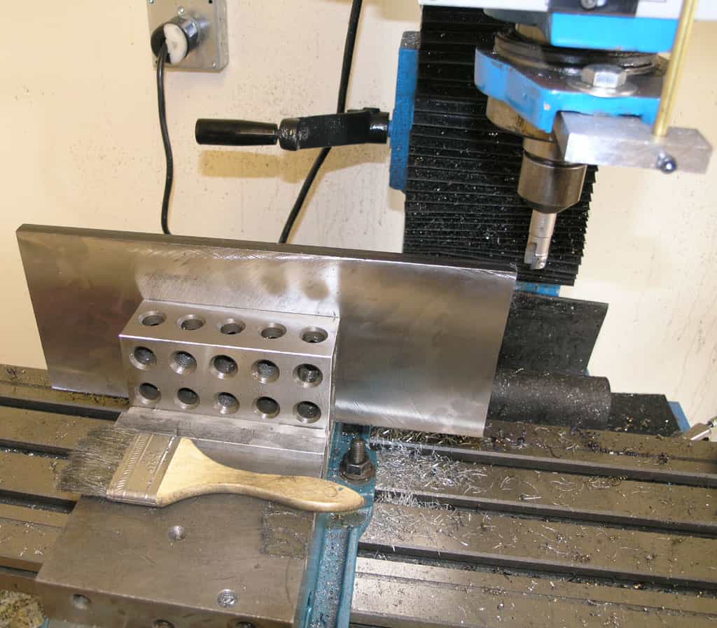 A metalworking vise with wooden handle on a milling machine table.