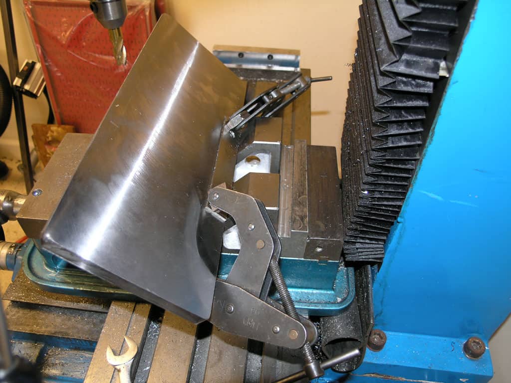 Metalworking vise on milling machine table in workshop.