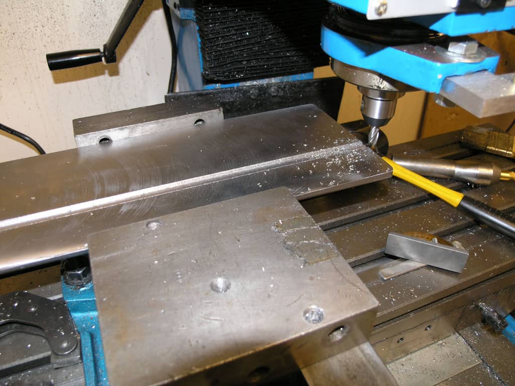 Industrial metalworking machine shop with large lathe or milling machine, blue metal working vise, and various tools.