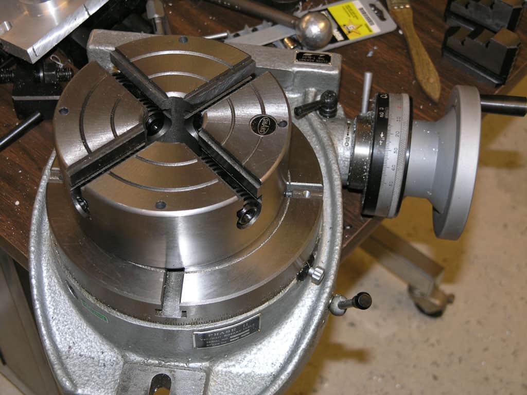 Heavy-duty precision vise mounted on lathe or mill, featuring robust metal construction and adjustable jaws for secure workpiece holding.