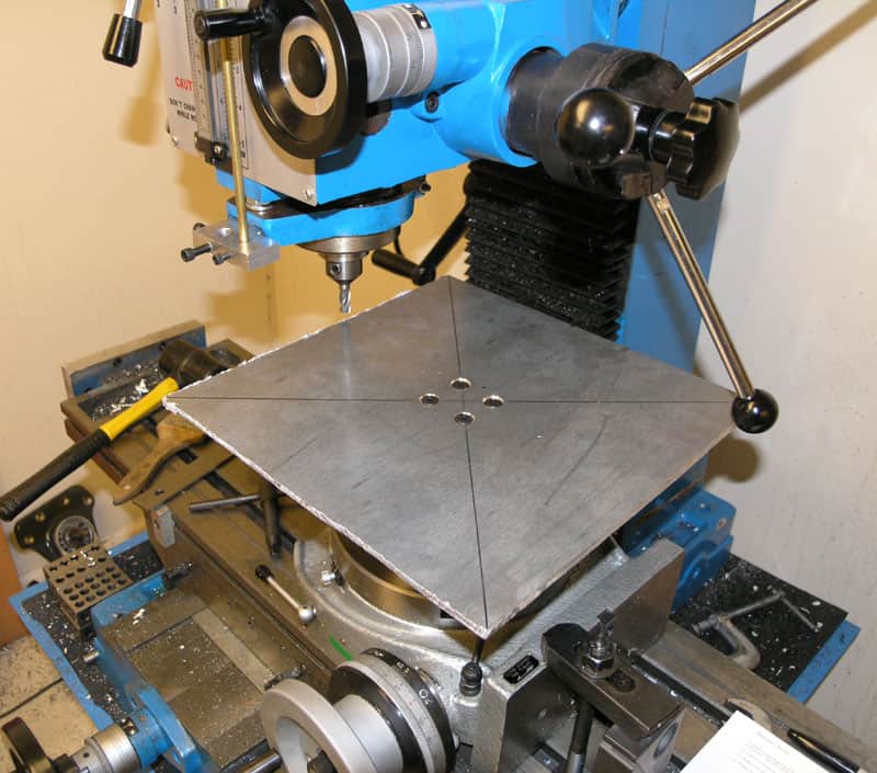 Blue and silver metalworking machine with surface plate and various tools and attachments visible.