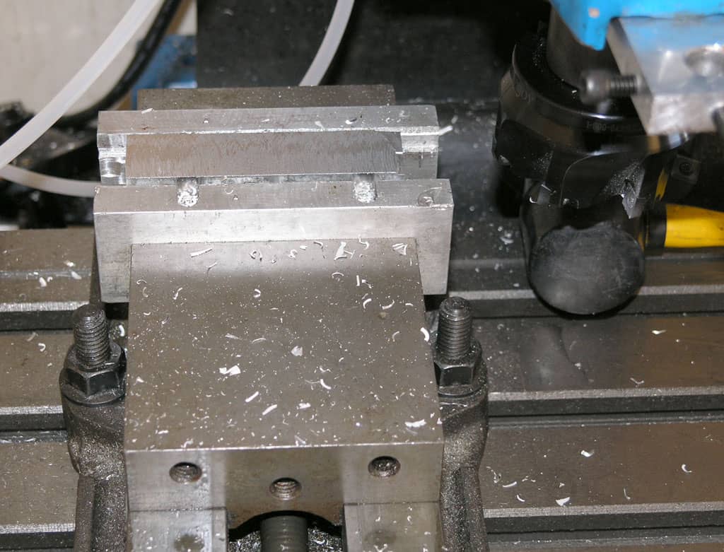 Metalworking vise on a metal base plate in a workshop.