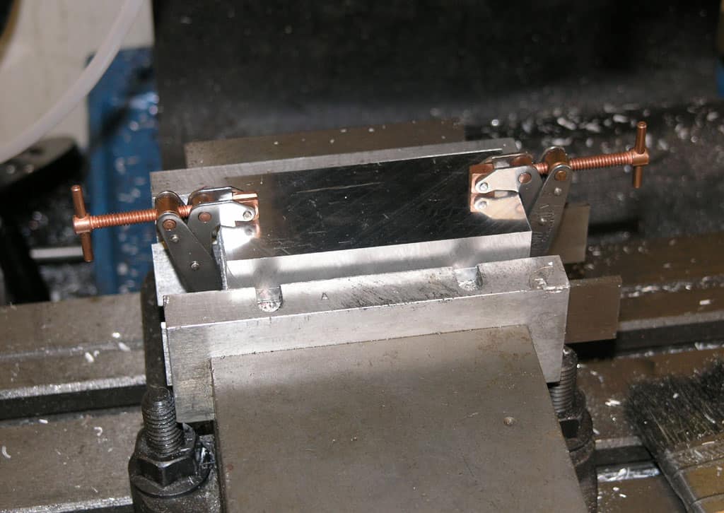 Metal vise holding aluminum or silver metal part in place.