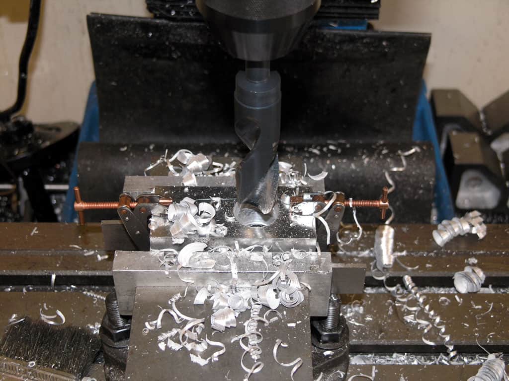 Metalworking lathe with metal components and shavings on its surface.