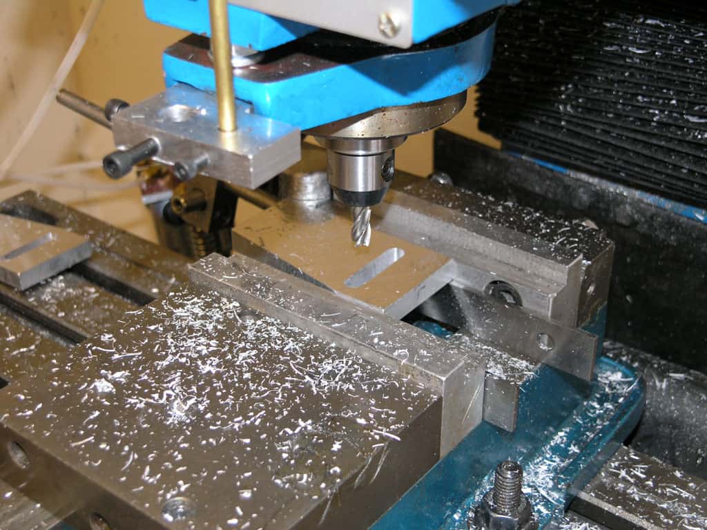 A milling machine's spindle with metal shavings and debris in a workshop/factory setting.