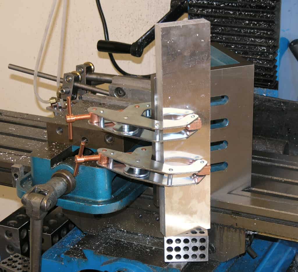 Lathe setup with copper clamps and blue vise on a machine shop floor.