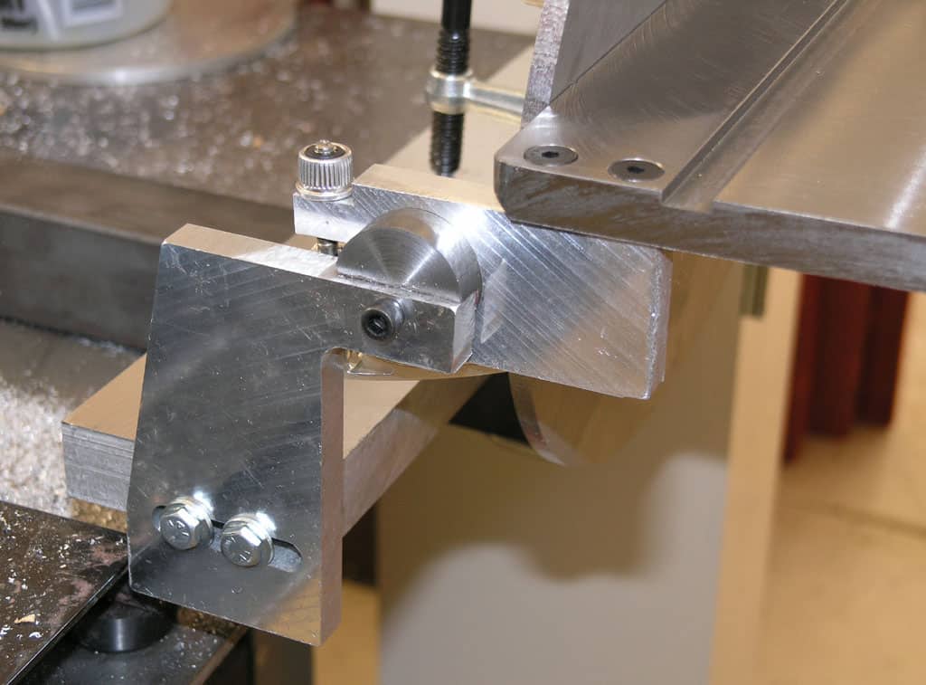 Metalworking vise with adjustable jaw, silver-colored, on workbench.