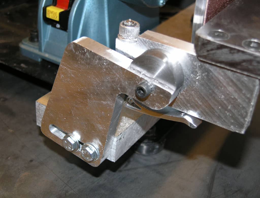 Metal vise attached to workbench in a workshop setting with machinery in background.