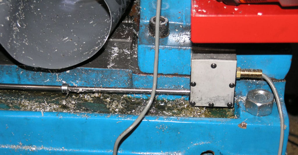 Blue metalworking lathe with red component, covered in debris and dust.
