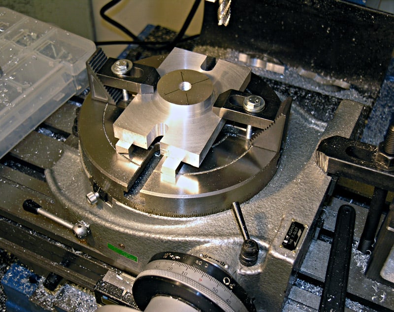 Metalworking lathe or milling machine rotary table with cross-shaped object at center.