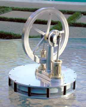 Circular plastic or acrylic wheel with four spokes on a cylindrical stand submerged in shallow water.