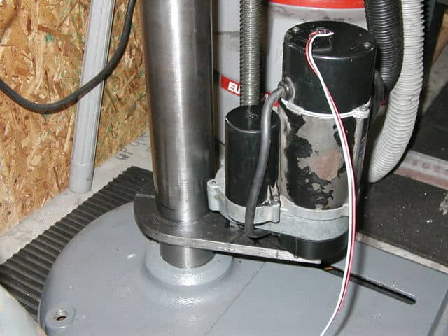 Metal component with cylindrical shape, flat base, and threaded rod on a gray industrial surface.