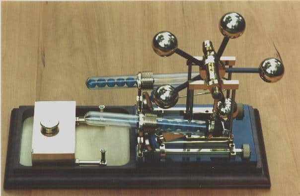 Antique telegraph key with moving balls on rods for sending Morse code messages.