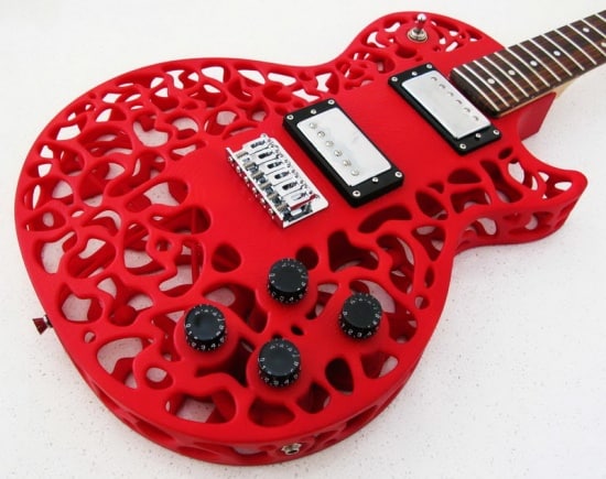 A red 3D printed electric guitar with atom-inspired design and intricate cutouts.