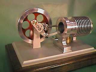 Small cylindrical metal device with central hole and ridged surface on a base plate.