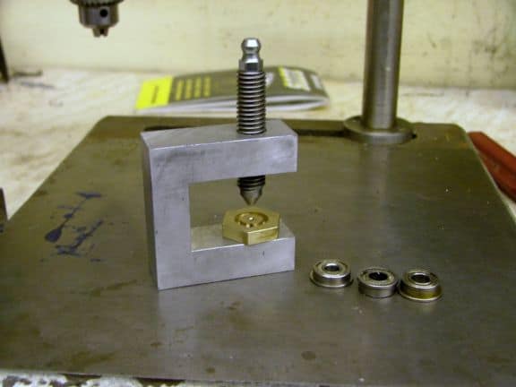 Metal press tool with two small washers on its surface.