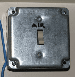 Square metal plate with black lettered word AIR and central switch.