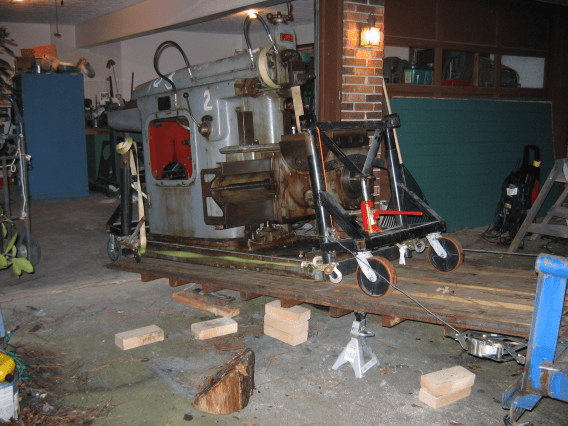 Large metal lathe on wooden platform in industrial setting.