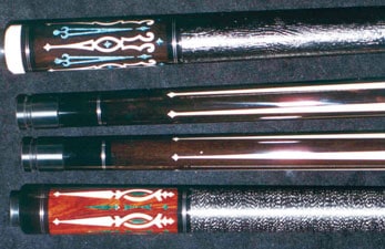Three pool cues with intricate inlay designs on their handles featuring dark, light, and medium wood tones with contrasting colors.