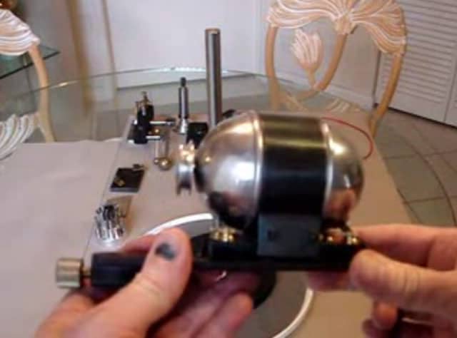 Micrometer held by a hand in front of metal fabrication equipment.