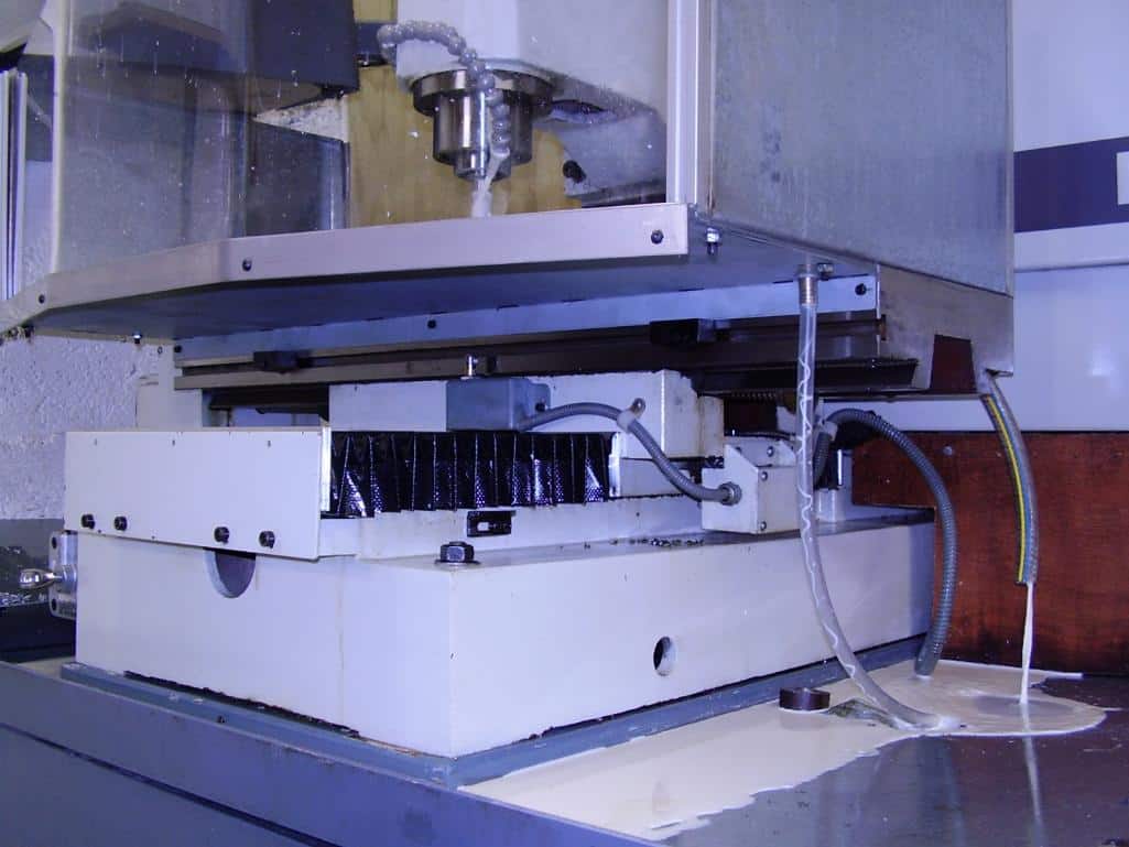Large industrial machine with white base and various components attached, possibly a cutting or milling tool.